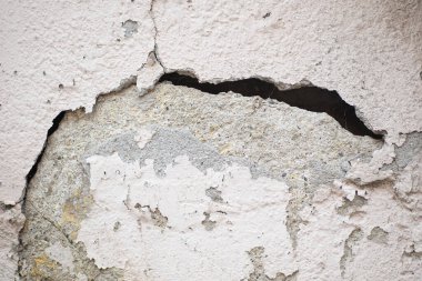 Duvarda görünür çatlaklar ve soyulmuş boyalar var. Bu da yıpranma ve yaşlanmayı gösteriyor..