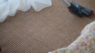 Bir insan sıcak ve davetkar bir odada güneş ışığıyla halıyı süpürür..