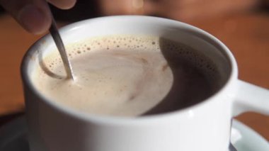 Sıcak bir kafede zengin bir fincan kahveyi karıştırmak.