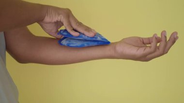 Ağrı kesici ve iyileşme için bir koldaki buz torbasının nasıl kullanılacağını gösteriyor..