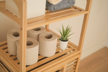 Tahta bir rafta düzgün düzenlenmiş havlular ve tuvalet kağıdı ruloları..