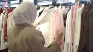 Bir insan canlı bir butik ortamında renkli giysileri keşfeder..