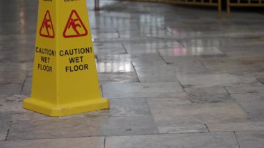 Uyarı levhası, ziyaretçileri yoğun bir alandaki ıslak zemine uyarır..