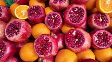 Parlak nar ve portakallar hareketli bir pazarda sergilenir.