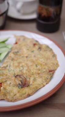 Sebzeli omlet, yanında yeşillik olan bir tabakta servis ediliyor..