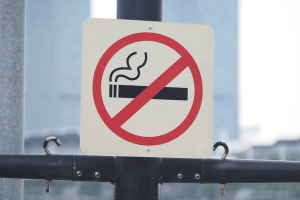 This sign displays a clear no smoking message near a busy urban area.