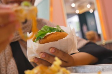 Canlı bir kafede otururken nefis bir sandviç tutan kişi..