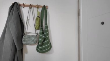 Paltolar ve çantalar, basit bir yerde, duvardaki kancaya düzgün bir şekilde yerleştirilmiştir..