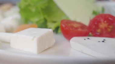 Parlak salata tabakta taze domates, peynir ve yeşillik içerir..