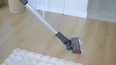 Kablosuz süpürge, geniş ve parlak bir alanda parke zeminleri temizler..