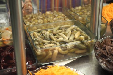 Assorted pickled vegetables are neatly arranged in containers at a buffet.