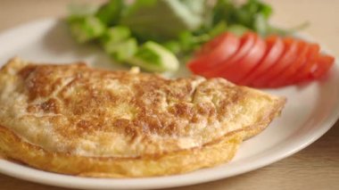 Taze yeşillik ve dilimlenmiş domatesle lezzetli bir omletin tadını çıkar..