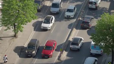 Öğlen saatlerinde açık gökyüzünün altında yoğun şehir yolları boyunca arabalar durmadan hareket eder..