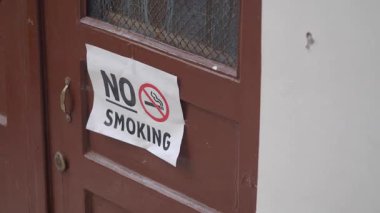 Kahverengi ahşap bir kapıda sigara içilmez işareti var..