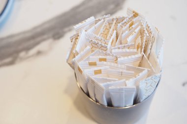 Küçük şeker paketleri dikkatle gümüş bir tutacağa konur..