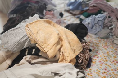 Yatağın üzerine bir yığın temiz giysi saçılmış. Bu da çamaşır günü karmaşasını akla getiriyor..