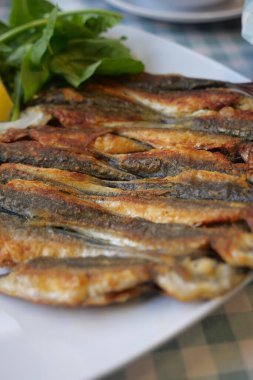 Taze otlar ve limon dilimleriyle dizilmiş lezzetli kızarmış balıklar..