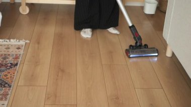 Kişi, rahat bir odada ahşap döşemeleri süpürür, temizliği sağlar..