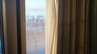 Yumuşak ışık perdelerin arasından süzülür, güzel bir kıyı manzarası ortaya çıkar..