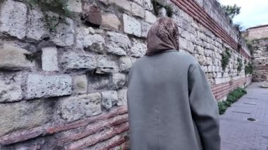 İstanbul 'da antik taş duvarlar boyunca yürüyen bir kadın tarihi keşfediyor..