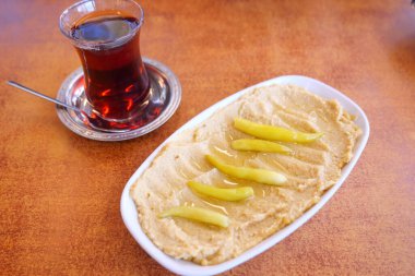 Tatlı dilimlerle kaplı yumuşak bir tatlı, sıcak bir fincan çayla eşleştirilmiş..