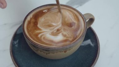 Yetenekli bir barista sıcak bir kafede çarpıcı bir latte sanatı yaratıyor..