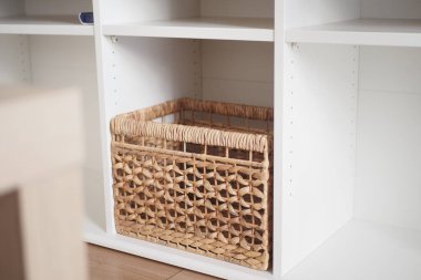 Beyaz bir rafta örülmüş bir sepet uzaya sıcaklık ve doku katar..