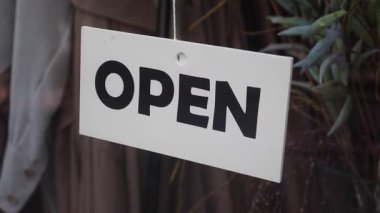 Bir mağaza, müşterileri içeri girip göz atmaya davet eden bir açık tabela gösterir.