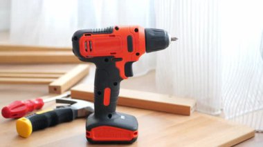 Bir matkap ve çeşitli aletler güneş ışığıyla ahşap bir yüzeye oturur..