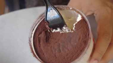 Kakao tozuyla kaplı kremalı bir tatlıyı karıştıran bir insan..