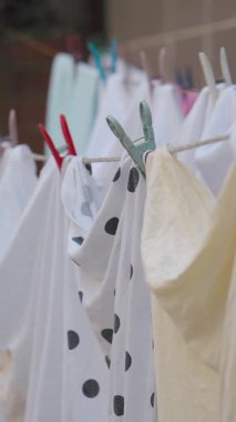 Değişik renklerde elbiseler sıcak güneş ışığında bir çizgide asılı duruyor..