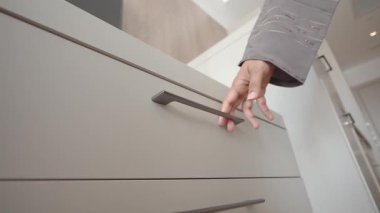 Gösterişli, şık bir mutfakta çekmeceyi açmak için uzanır..