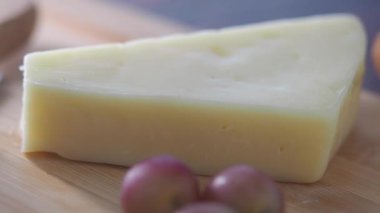 Lezzetli peynir parçaları, yakınlarda taze üzümler olan tahta bir tahtanın üzerinde duruyor..