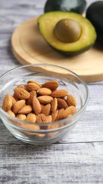 Tahta bir yüzey üzerinde taze badem ve avokado gösterisinin tadını çıkarın..