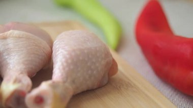 Kesme tahtasının üzerinde renkli biberlerle çiğ tavuk bacağı hazırlıyorum.