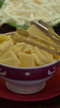 Peynir dilimleri kolay servis için maşayla bir kasede sergilenir..