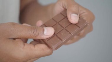 Bir insan bir çikolatayı tutar, tatlı tadını çıkarmaya hazırdır..