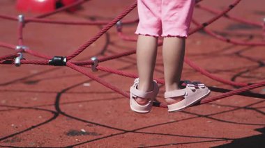 Bir çocuk oyun parkında ip yapısını keşfedip tırmanır..