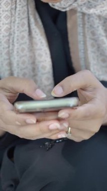 Bir insan dışarıda otururken akıllı telefonuyla meşgul olur..