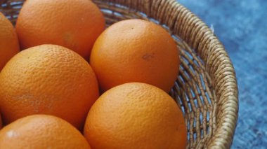 Parlak portakallar dokulu mavi arka planda bir sepette dinlenirler..