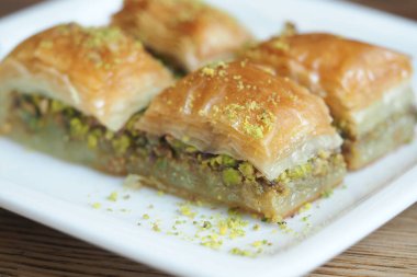 Baklava beyaz bir tabakta sunuluyor, içinde hamur ve fındık katmanları var..
