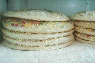 Dondurulmuş birkaç pizza düzgünce bir dondurucuda saklanıyor..
