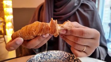 Bir insan büyüleyici bir kafede gevrek bir kruvasan kırar..