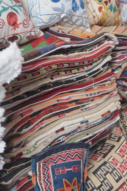 Güzelce dokunmuş tekstil yığınları karmaşık desenler ve renkler sergiliyor.