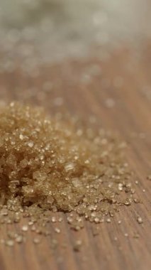Tahta bir masanın üzerinde kahverengi şeker kristallerinin yakın plan görüntüsü..