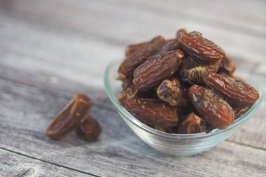 Bir kase ahşap bir masada taze tarihlerle doludur. Bazı tarihler yakın..