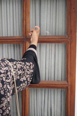 Siyahlı bir insan nazikçe ahşap bir kapıyı çalar..