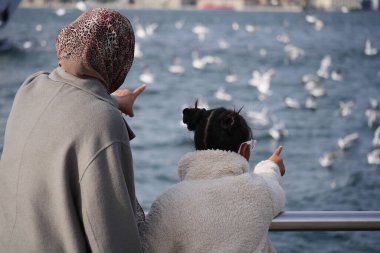 Bir kadın ve bir çocuk, sudaki kuşları onları işaret ederken izliyorlar..