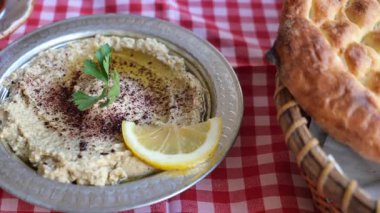 İnsanlar yemekteki bir masada humus ve ekmeği paylaşıyor..