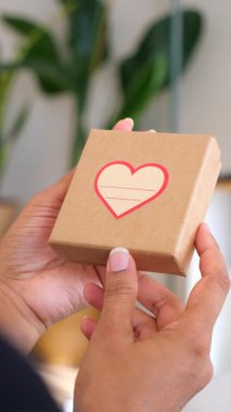 Bir insan, içinde kalp tasarımı olan küçük bir hediye kutusu gösterir. Ayarlarda bitkiler var..